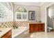 Bright bathroom featuring a soaking tub, vanity with granite counters, and arched window with plantation shutters at 3986 Se 43Rd Cir, Ocala, FL 34480