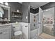Gray toned bathroom featuring white wainscoting, a subway tile shower, and decorative floating shelves at 460 E Haines Blvd, Lake Alfred, FL 33850