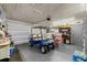 Spacious garage with a blue golf cart, epoxy flooring, shelving, and ample storage space at 460 E Haines Blvd, Lake Alfred, FL 33850