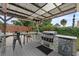 Covered outdoor kitchen with a built-in grill, bar seating, and a mini-fridge, perfect for al fresco dining at 460 E Haines Blvd, Lake Alfred, FL 33850