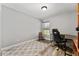 Bright bedroom with neutral walls and flooring, large window, and dark wood desk and gaming chair at 5133 Sw 41St Pl, Ocala, FL 34474