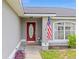 Inviting front entrance with a decorative red door, complimented by an American flag and well maintained landscaping at 63 Walnut Crse, Ocala, FL 34480