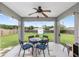 Relaxing covered patio with ceiling fan, outdoor lighting, and views of the spacious, green backyard at 63 Walnut Crse, Ocala, FL 34480