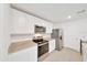 A large granite kitchen island is flanked by a stainless appliance suite and bright white cabinets at 7133 Sw 135Th Pl, Ocala, FL 34473