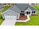 An aerial of a single-story home with a two-car garage, manicured lawn, and tasteful landscaping at 8289 Se 159Th Ln, Summerfield, FL 34491