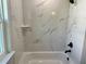 Elegant bathtub features tiled walls, a corner shelf, and a modern black faucet at 8289 Se 159Th Ln, Summerfield, FL 34491
