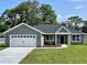 Charming single-story home with a well-manicured lawn, attached two-car garage, and beautiful landscaping at 8289 Se 159Th Ln, Summerfield, FL 34491