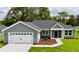 Charming single-story home with a well-manicured lawn, attached two-car garage, and beautiful landscaping at 8289 Se 159Th Ln, Summerfield, FL 34491