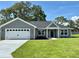 Charming single-story home with a gray exterior, a two-car garage, and a well-manicured lawn at 8289 Se 159Th Ln, Summerfield, FL 34491