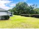Expansive backyard showcasing lush green grass, mature trees, privacy hedges, and a screened lanai at 9328 Sw 192Nd Court Rd, Dunnellon, FL 34432