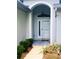 Close-up of the home's light blue front door, complete with an arched entryway, and manicured landscaping at 9328 Sw 192Nd Court Rd, Dunnellon, FL 34432