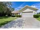 Charming home exterior with a spacious driveway, manicured bushes, and a two-car garage at 95 Hickory Loop, Ocala, FL 34472