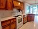 Traditional kitchen features knotty pine cabinets, white appliances, and tile backsplash at 95 Hickory Loop, Ocala, FL 34472