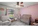Cozy Bedroom features a crib, rocking chair, window with soft lighting, and plush carpeting at 986 Se 57Th Ave, Ocala, FL 34480