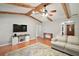 Open-concept living area with wood floors, beamed ceilings, and a stylish TV cabinet with shelving at 986 Se 57Th Ave, Ocala, FL 34480