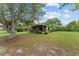 Single-story home with a screened porch, carport, and mature trees on a sprawling green lawn at 10012 Sw 88Th Ct, Ocala, FL 34481