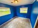 Bedroom with blue walls, light-colored tile flooring, two windows and ceiling light at 1051 Se 28Th Rd, Ocala, FL 34471