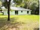 Backyard featuring green lawn, trees and the home's rear facade with sliding glass doors at 13921 Sw 108Th Ln, Dunnellon, FL 34432