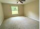 This bedroom features neutral carpet, a ceiling fan, and a window for natural light at 13921 Sw 108Th Ln, Dunnellon, FL 34432