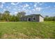 This home features a spacious backyard with a grassy area and a sliding glass door entrance at 142 Guava Pass, Ocklawaha, FL 32179