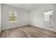 Serene bedroom with wood-look floors and a view of nature from the window, leading to an ensuite bathroom at 142 Guava Pass, Ocklawaha, FL 32179