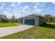 Charming single-story home with a blue garage door, gray exterior and long concrete driveway at 142 Guava Pass, Ocklawaha, FL 32179