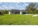 Charming single-story home with a blue garage door, gray exterior and a well-manicured lawn at 142 Guava Pass, Ocklawaha, FL 32179