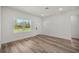 Bright living room with wood-look flooring, white trim, and a large window offering views of lush greenery at 142 Guava Pass, Ocklawaha, FL 32179