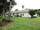 Rear view of the home with an expansive yard and meticulous landscaping with screened in patio at 14695 Sw 112Th Cir, Dunnellon, FL 34432