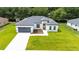 Charming single-story home featuring a modern facade, well-manicured lawn, and a gray two car garage door at 162 Nw 42Nd Pl, Ocala, FL 34475