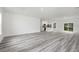 Bright living room with gray wood floors opens to modern kitchen with white cabinetry at 162 Nw 42Nd Pl, Ocala, FL 34475