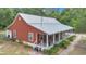 A red house has a metal roof and a large porch with nice landscaping at 23608 Ne 124 Place Rd, Salt Springs, FL 32134