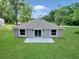 A spacious grassy backyard with a concrete patio and sliding glass doors for seamless indoor-outdoor living at 3696 Se 139Th Ln, Summerfield, FL 34491