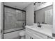 A bathroom offers a tub/shower with glass doors, a white vanity, and modern black fixtures at 3696 Se 139Th Ln, Summerfield, FL 34491