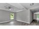 A bright bedroom with wood-look floors, a ceiling fan, neutral paint, and large window offering views of nature at 3696 Se 139Th Ln, Summerfield, FL 34491