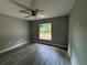 Cozy bedroom with hardwood floors, a ceiling fan, and a large window offering natural light at 3696 Se 139Th Ln, Summerfield, FL 34491