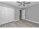 This bedroom has neutral walls, wood-look flooring, a ceiling fan, and a closet with white doors at 3696 Se 139Th Ln, Summerfield, FL 34491