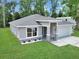 Beautifully landscaped front yard featuring a gray home with stone accents, a large window, and manicured lawn at 3696 Se 139Th Ln, Summerfield, FL 34491