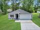 Charming single-story home with a gray facade, landscaped front yard, and two car garage nestled among mature trees at 3696 Se 139Th Ln, Summerfield, FL 34491