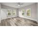 Bright bedroom featuring three windows, light-colored walls, ceiling fan and wood-look flooring at 4609 Ne 7Th St, Ocala, FL 34470
