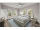 Bright bedroom featuring a bed, three windows, light-colored walls, ceiling fan and wood-look flooring at 4609 Ne 7Th St, Ocala, FL 34470