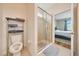 Bathroom with a toilet, storage, and glass-enclosed shower adjoining bedroom at 6318 Sw 89Th Lane Rd, Ocala, FL 34476