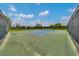 Community tennis court surrounded by a fence, set against a backdrop of trees and a cloudy sky at 6318 Sw 89Th Lane Rd, Ocala, FL 34476