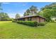 Brick home with manicured landscaping, a mature lawn, and a classic brick chimney at 6497 W Anthony Rd, Ocala, FL 34479