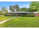 Charming brick home featuring a lush front lawn, mature trees, and a welcoming walkway leading to the front door at 6497 W Anthony Rd, Ocala, FL 34479