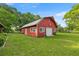 Quaint red outbuilding with white trim, roll up door, and lush green lawn at 6497 W Anthony Rd, Ocala, FL 34479