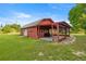 Side view of a red outbuilding with a covered patio and lush green lawn at 6497 W Anthony Rd, Ocala, FL 34479