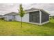An exterior shot of a screened in porch and a grassy backyard at 6877 Minchew Cir, The Villages, FL 34762