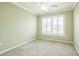 Empty bedroom featuring plush carpeting, a large window for natural light, and neutral paint at 6877 Minchew Cir, The Villages, FL 34762