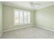 This empty bedroom has soft carpeting, a large window, and a neutral color palette at 6877 Minchew Cir, The Villages, FL 34762
